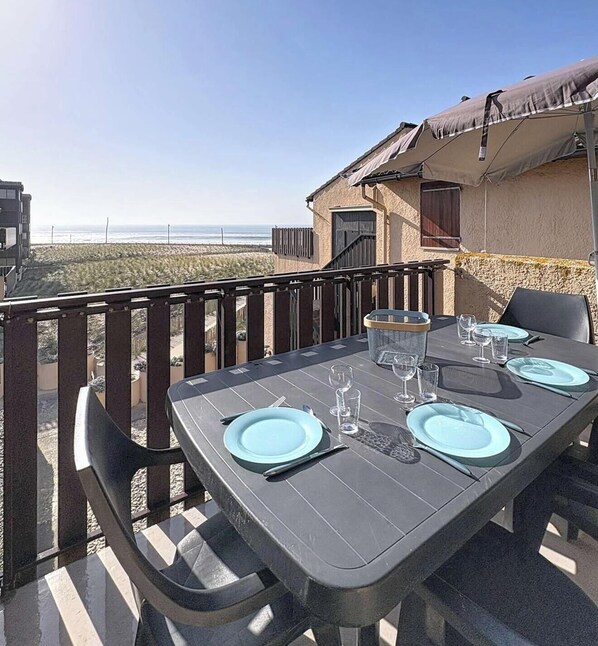 Ein Tisch für zwei Personen mit blauen Tellern und klaren Gläsern, mit Blick auf einen Strand.