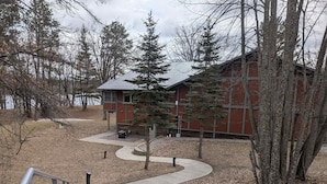 A building with a metal roof, surrounded by trees and a pathway leading to a staircase.