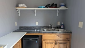 A compact kitchen with a dishwasher, a sink, and a dish rack.