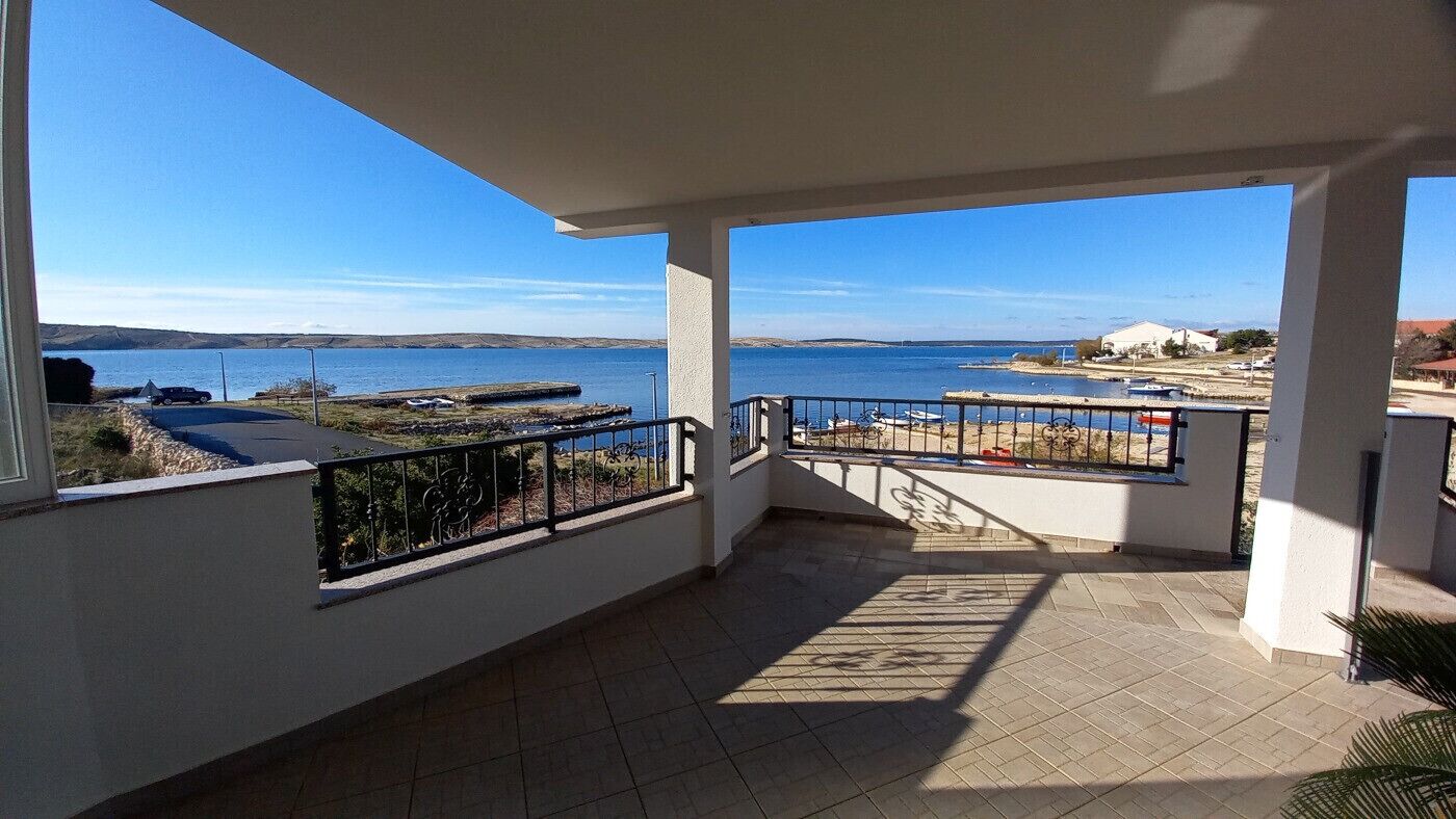 A balcony with a view of the sea and a distant shoreline.