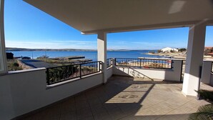 Un balcon avec vue sur la mer et sur une côte lointaine.