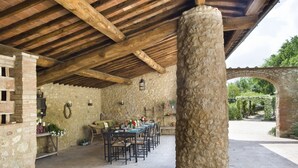 An outdoor patio with stone walls, wooden beams, and a brick archway. - Montestigliano, an authentic farmhouse in the heart of Tuscany, is an oasis of peace and beauty that offers its guests refined residences and an enchanting view (Sovicille)