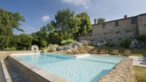 A swimming pool with lounge chairs, surrounded by stone walls and greenery. - Montestigliano, an authentic farmhouse in the heart of Tuscany, is an oasis of peace and beauty that offers its guests refined residences and an enchanting view (Sovicille)
