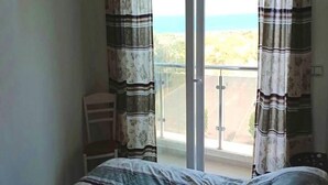 A bedroom with a bed, curtains, and a view of a balcony with a railing. - Beautiful Sea View Apartment in Saidia 4268 (Saidia)
