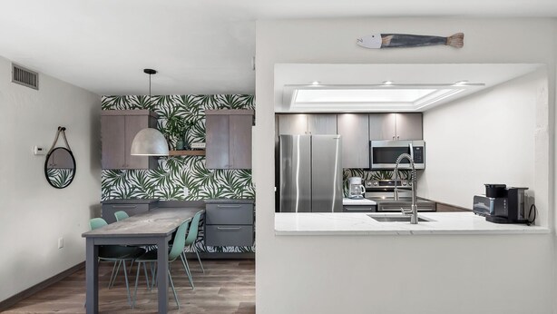 A modern kitchen with a central island, built-in appliances, and a dining area with a table and chairs. - Cozy Garden View 1 bed, 1 bath at Sanibel Moorings #212 (Sanibel)