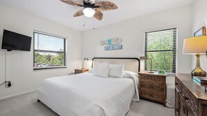 A bedroom with a bed, a nightstand, a lamp, a TV, and a ceiling fan. - Cozy Garden View 1 bed, 1 bath at Sanibel Moorings #212 (Sanibel)