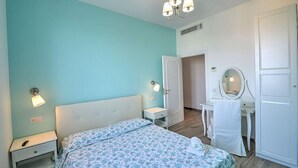Ein Schlafzimmer mit Bett, Nachttisch, Kommode, Spiegel und einer Pendelleuchte.