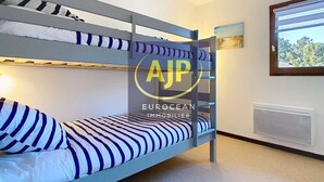 Dormitorio con literas, ventana y radiador.