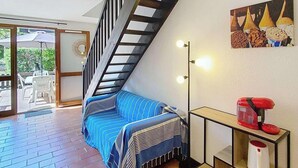 Una sala de estar moderna con una escalera de madera, un sofá azul a rayas, una cafetera y un cuadro en la pared.