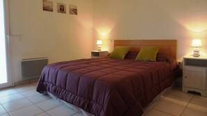A bedroom with a large bed, two bedside tables with lamps, and a radiator. - Magnifique T2 avec terrasse à 50m de la plage (094) (Biscarrosse)