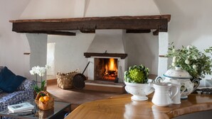 A cozy living room with a fireplace, a sofa, a coffee table, and decorative items. - Montestigliano, an authentic farmhouse in the heart of Tuscany, is an oasis of peace and beauty that offers its guests refined residences and an enchanting view (Rosia - Sovicille)
