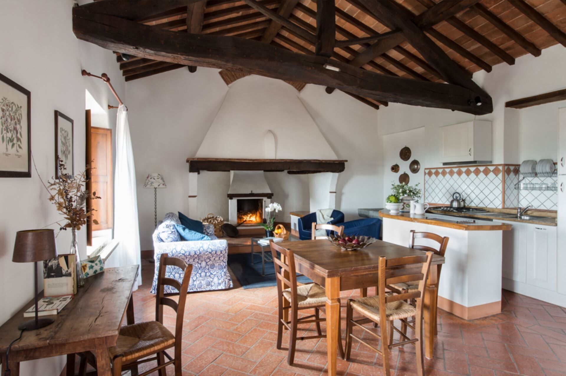 A rustic interior with a fireplace, wooden furniture, and a kitchen area.