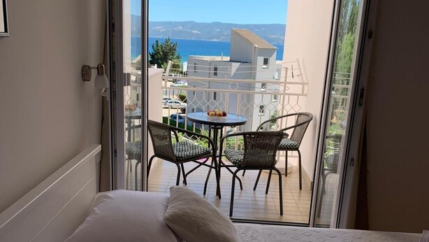 A bedroom with a bed, pillows, and a view of a balcony with a table and chairs. - Apartment in Duće with Seaview, Balcony, Air condition, WIFI (4174-7) (Duce)