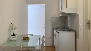 A compact kitchen with a sink, a small refrigerator, and a dining area with a table and chairs. - Apartment in Duće with Seaview, Balcony, Air condition, WIFI (4174-7) (Duce)