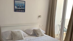 A neatly made bed with a patterned bedspread, a painting of boats on the wall, and a view of the outdoors through a sliding glass door. - Apartment in Duće with Seaview, Balcony, Air condition, WIFI (4174-7) (Duce)
