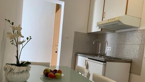 A modern kitchen with a glass table, white chairs, and a bowl of fruit. - Apartment in Duće with Seaview, Balcony, Air condition, WIFI (4174-7) (Duce)