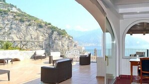 Una terrazza con mobili da esterno, un'area pranzo e vista sul mare e sulle montagne.