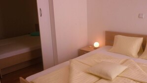 Un lit bien fait, avec une couette blanche et des oreillers, une lampe de chevet et une table de chevet en bois.