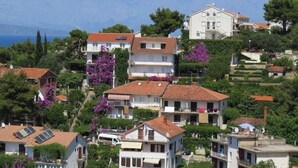 A hillside residential area with terraced houses, some with balconies, and a view of the sea in the background. - Apartment in Jelsa with Balcony, Air condition, WIFI (3621-1) (Jelsa)