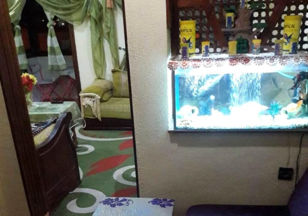 Une pièce comprenant un lit, une petite table avec un vase, un aquarium et une étagère sur laquelle sont disposés divers objets.
