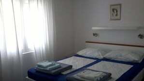 Une chambre d’hôtel avec un lit, une table de chevet, une fenêtre avec des rideaux et un tableau au mur.