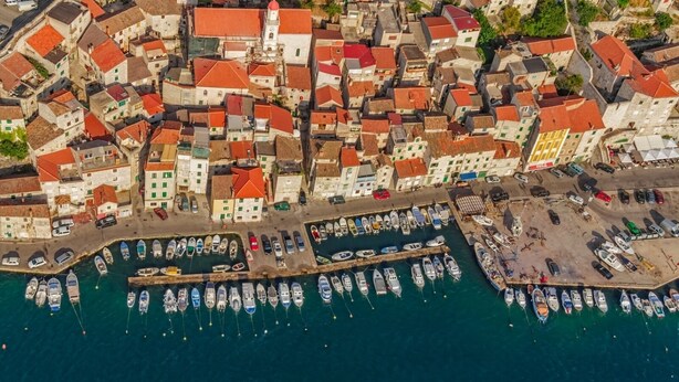 An aerial view of a coastal town with tightly packed buildings, a marina with numerous boats, and a prominent church with a red roof. - Apartment in Grebaštica with Seaview, Balcony, Air condition, WIFI (3571-2) (Grebaštica)