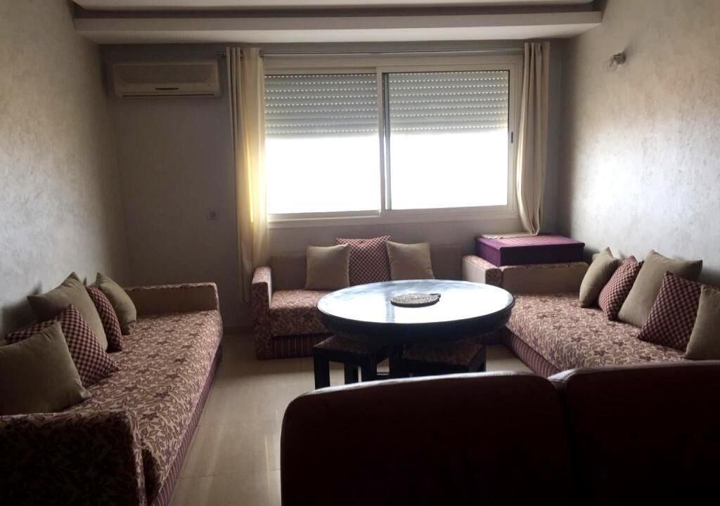 Sala de estar con un sofá, una mesa de centro redonda y una ventana con persianas.