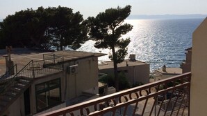 Un balcon avec vue sur la mer, un escalier et un arbre.