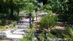 Un jardin agrémenté d’escaliers en pierre, de différentes plantes et d’une statue.