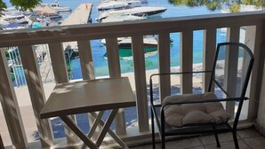 Un balcon donnant sur un port de plaisance, une chaise en métal avec un coussin et une petite table.