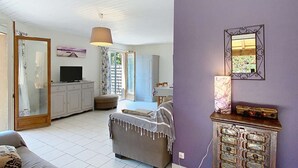 A spacious living area with a sofa, a television, a cabinet, and a dining area with a table and chairs.