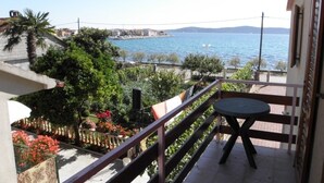Un balcón con vistas al mar, una mesa y plantas en macetas.