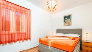 A bedroom with a bed, a nightstand, a lamp, a painting on the wall, and a window with sheer curtains. - Apartment in Pisak with Seaview, Terrace, Air condition, WIFI (102-4) (Pisak)