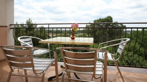 A balcony with two wicker chairs and a small table, a vase with flowers, and a view of greenery and trees. - Apartment in Poreč with Balcony, Air condition, WIFI (3794-5) (Porec)