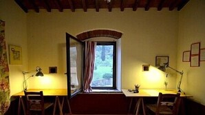 Une pièce avec une fenêtre, deux bureaux, deux chaises et deux lampes.