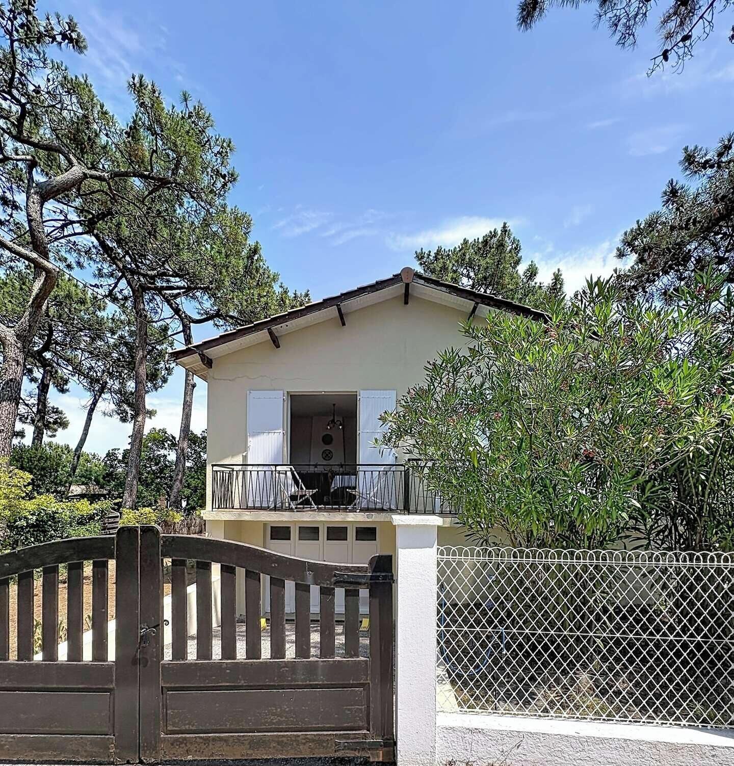 Ein zweigeschossiges Haus mit Balkon, umgeben von Bäumen.