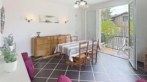 A dining area with a table and chairs, a wooden cabinet, and a balcony with a railing.