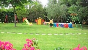 A grassy area with playground equipment including swings, slides, and a small playhouse. - Villa Sandia D: A welcoming apartment. (Castiglion fiorentino)