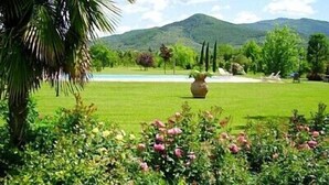 A well-maintained garden with a variety of plants and flowers, a large vase, and a view of a mountain in the background. - Villa Sandia D: A welcoming apartment. (Castiglion fiorentino)