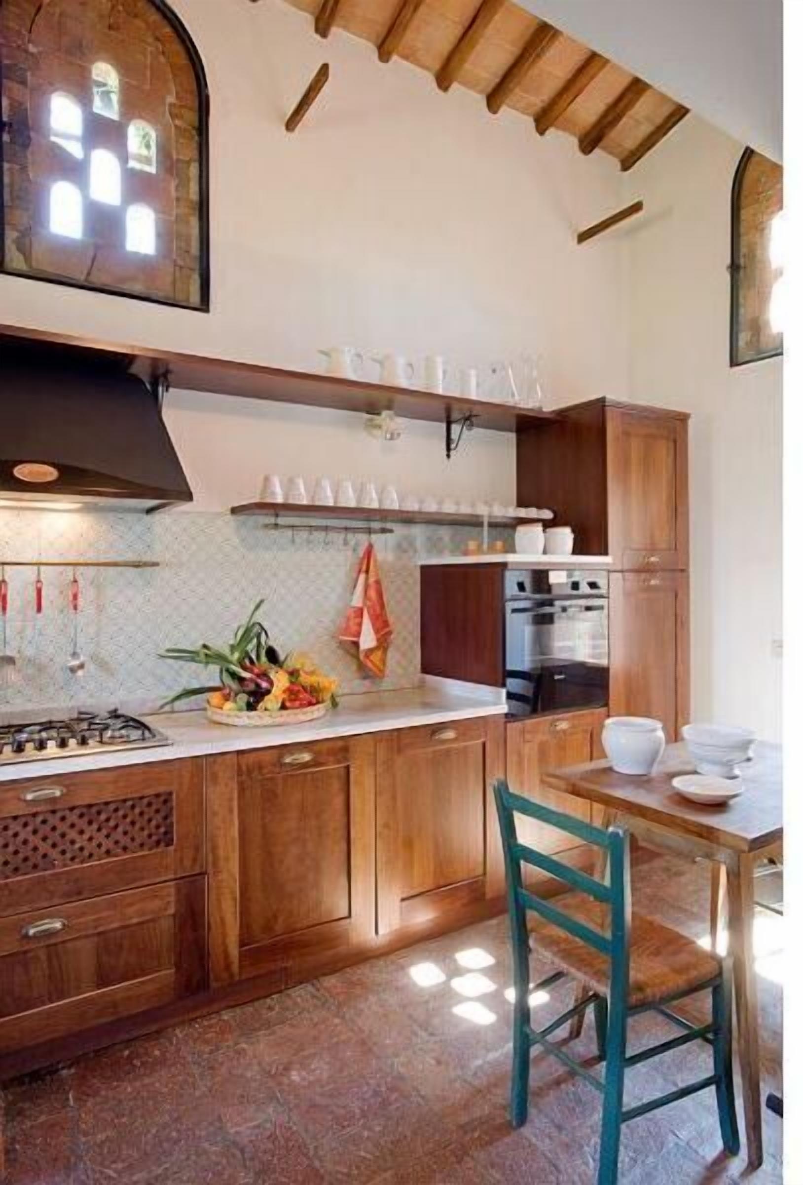 A kitchen with wooden cabinets, a gas stove, and a dining area with a table and chairs.