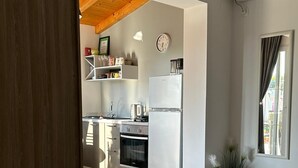 A modern kitchen with white cabinets, a built-in oven, and a refrigerator. There is a wooden ceiling and a potted plant by the window. - Studio apartment in Trpanj with Terrace, Air condition, WIFI, Washing machine (4199-5) (Trpanj)