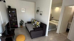 A modern, well-lit living room with a sofa, a small table, a TV, and a bookshelf. - Studio apartment in Trpanj with Terrace, Air condition, WIFI, Washing machine (4199-5) (Trpanj)