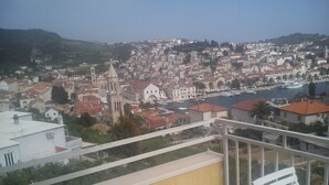 Un balcon offrant une vue sur une ville côtière, avec notamment une église imposante et un port de plaisance.