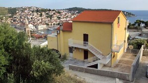 Un bâtiment jaune avec un toit rouge, un balcon et une vue sur une ville côtière.