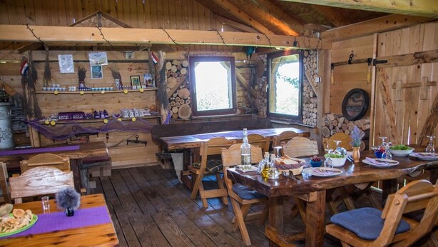 Un intérieur rustique en bois, avec un coin repas, des tables et des chaises en bois.