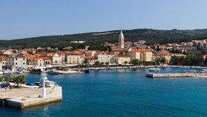 Une ville côtière dotée d’un clocher d’église imposant, d’un port de plaisance avec des bateaux, et d’un mélange de bâtiments traditionnels et modernes.