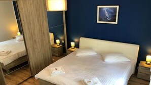 Een hotelkamer met een groot bed, twee nachtkastjes met lampen, een spiegel en een ingelijst schilderij aan de muur.