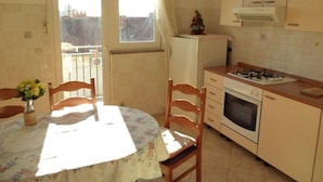 A compact kitchen with a dining table, chairs, a refrigerator, and a stove.