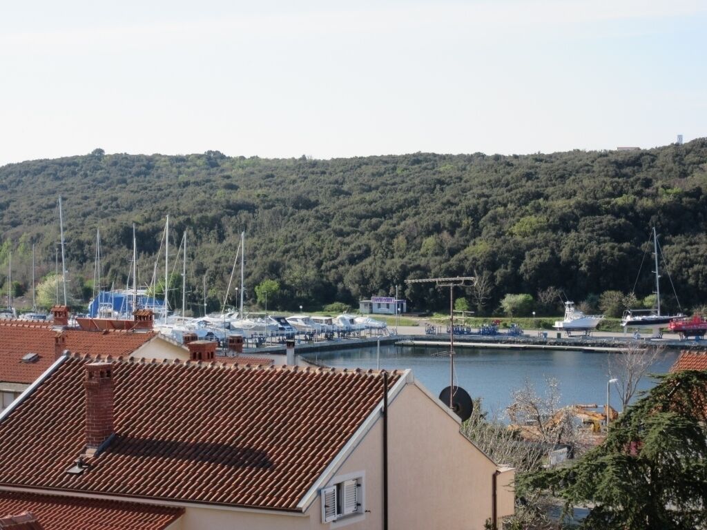 A coastal view with a marina, boats, and a hilly backdrop.