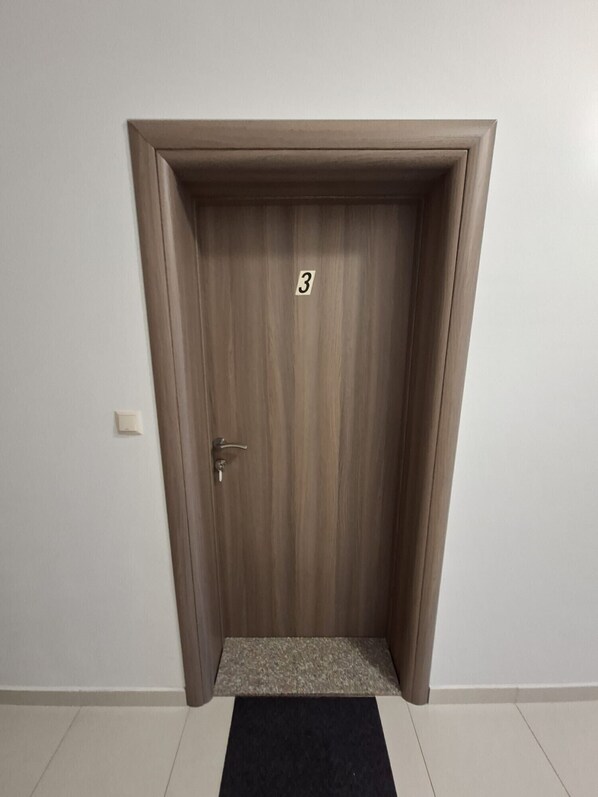 Eine geschlossene Tür mit der Zahl 3, einem Türknauf und einer kleinen Stufe zum Boden.